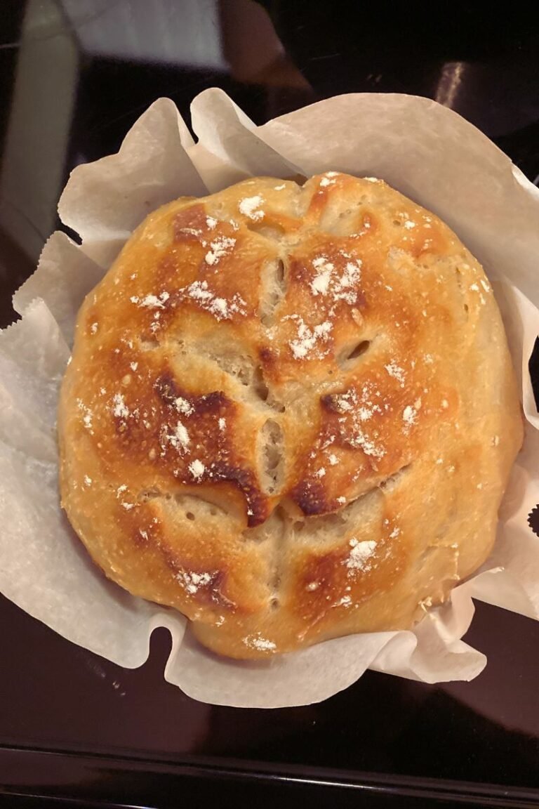 A fresh baked loaf of sourdough bread scored with a leaf pattern.